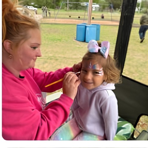 Sabrina painting a unicorn horn design outdoors